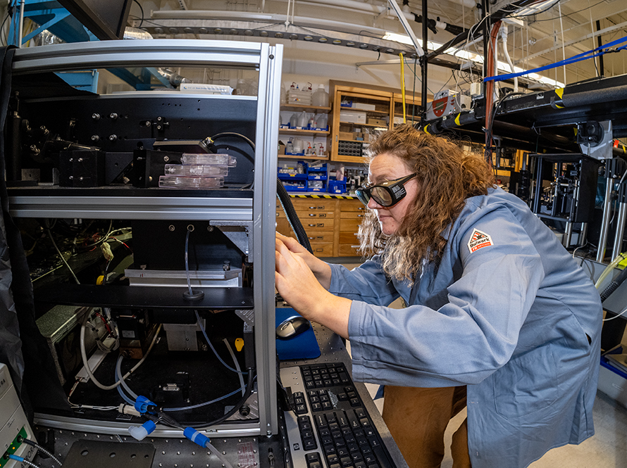 scientist in blue coat looking at scientific equipment closely